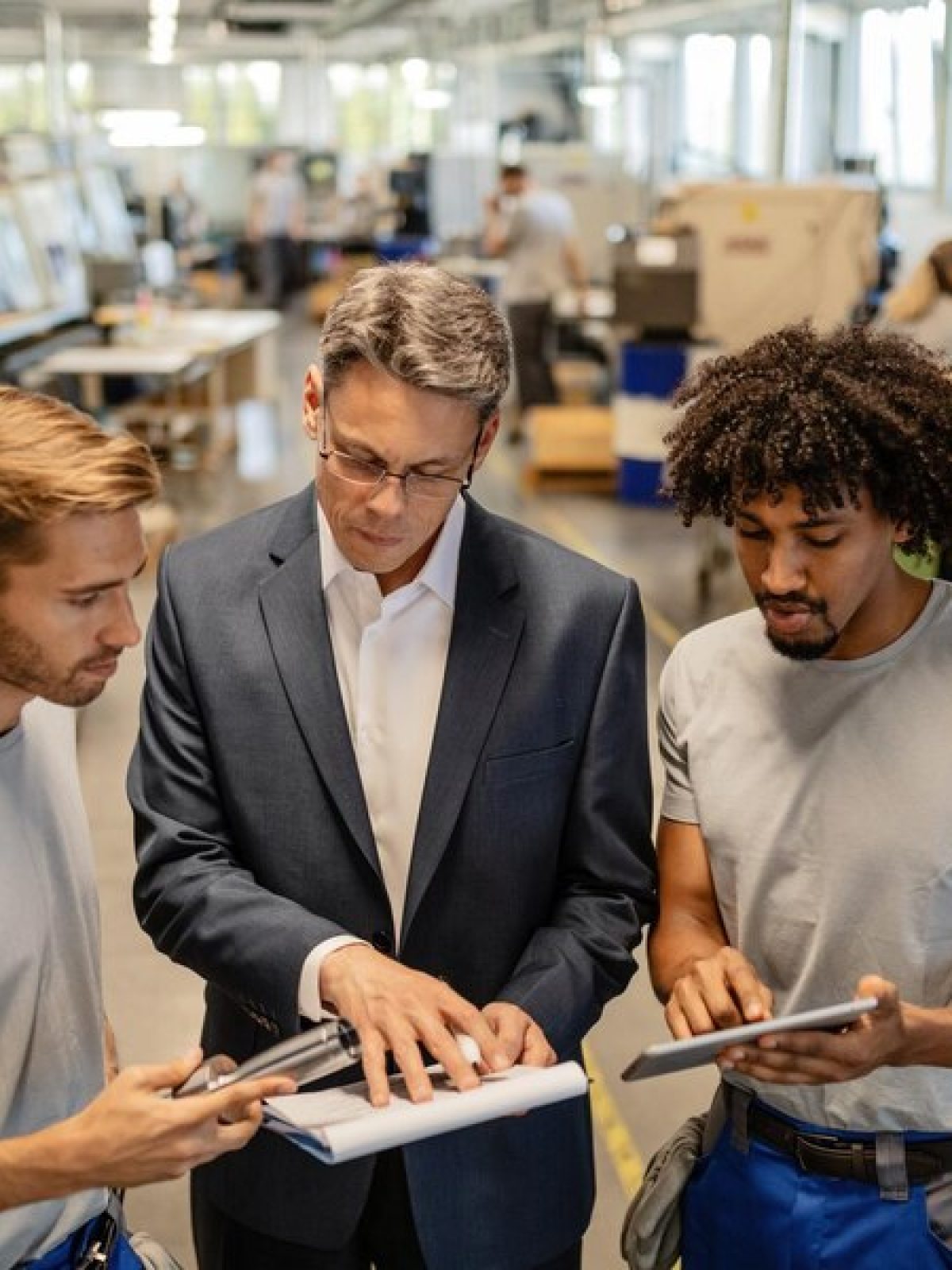 mid-adult-engineer-two-steel-workers-going-through-quality-reports-while-working-industrial-building_637285-4094